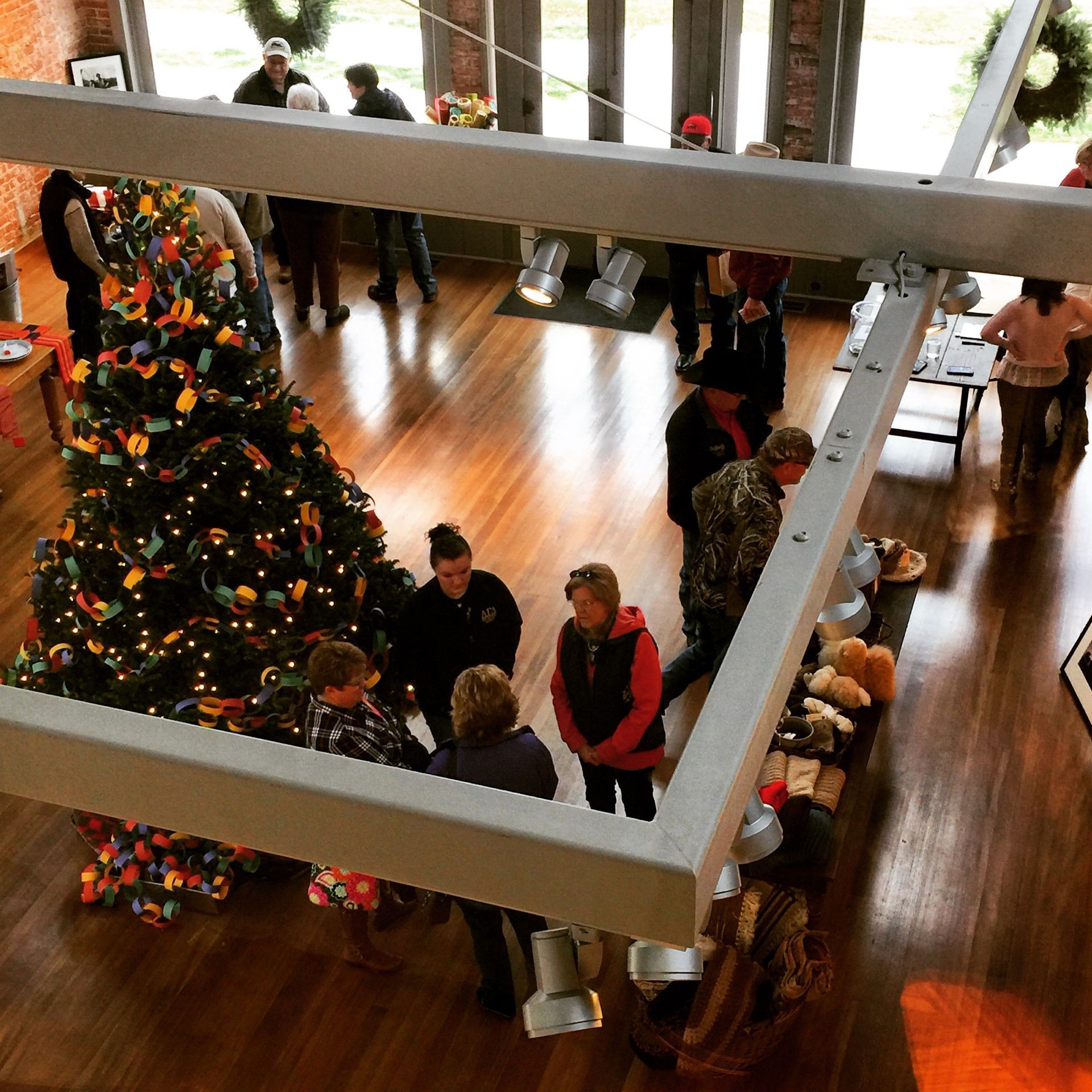 Christmas tree surrounded by people in a wood-floored room.