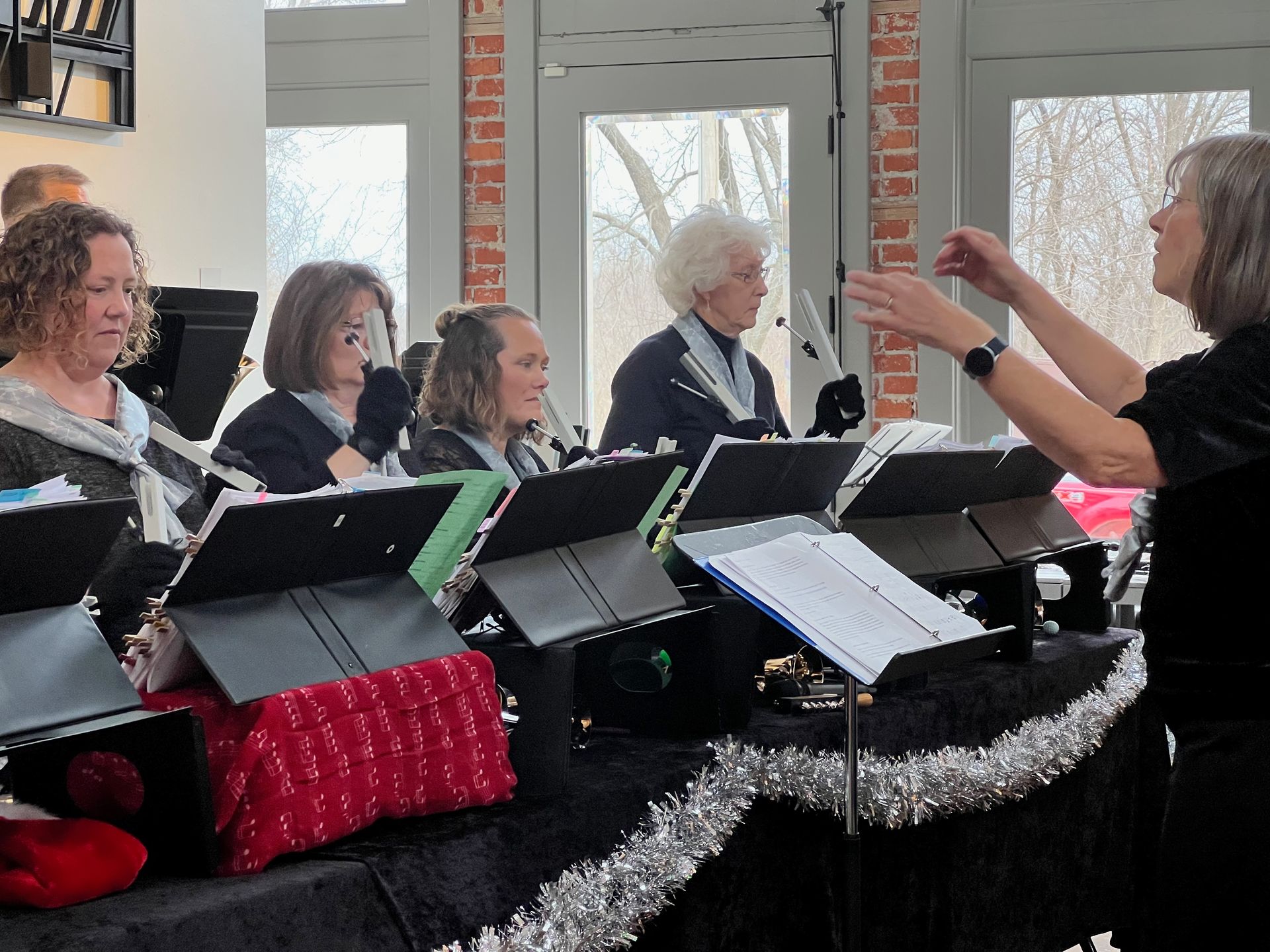 four musicians play bells in an interior space