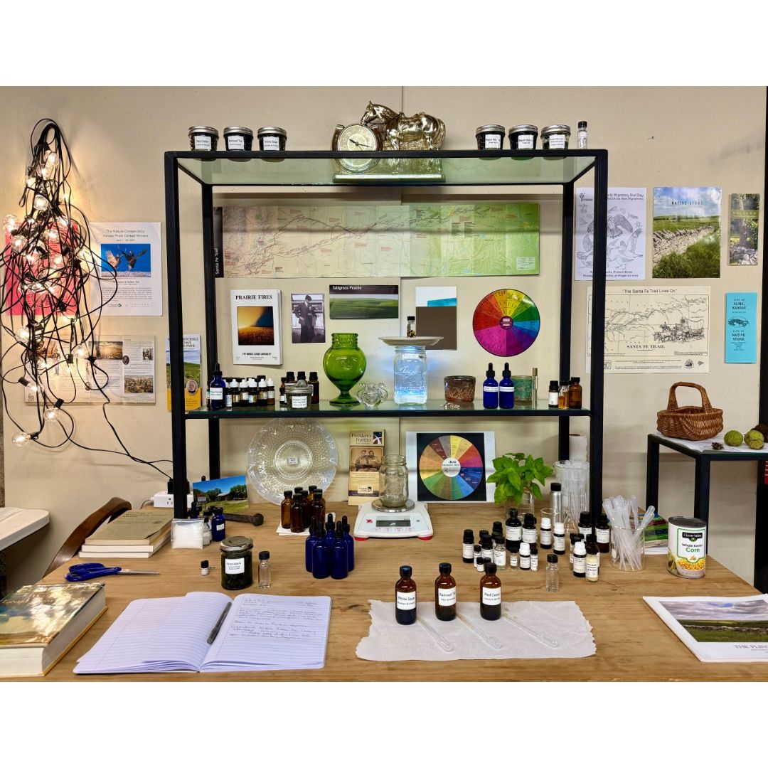 Desk with perfume bottles, color wheels, and jars; an artistic workspace with a shelf.