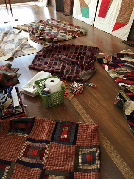 A bunch of quilts are laying on a wooden floor