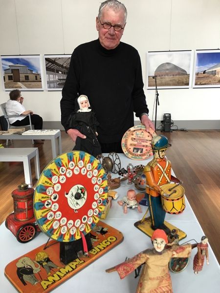 A man is standing in front of a table full of old toys