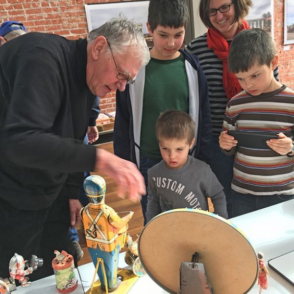 A man wearing a custom motors shirt looks at a toy