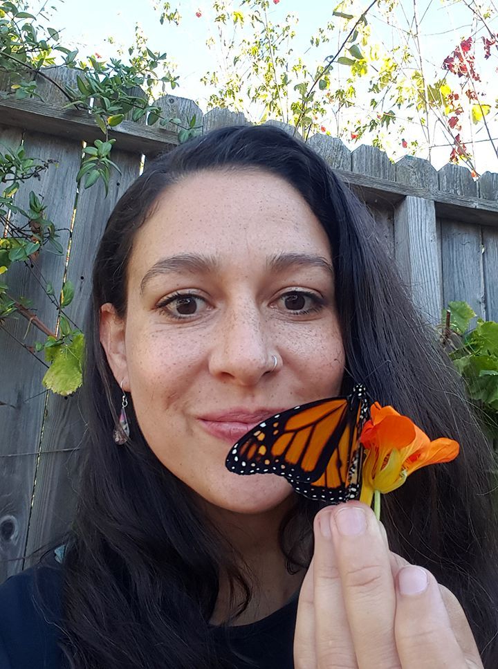 A woman is holding a butterfly in front of her face.