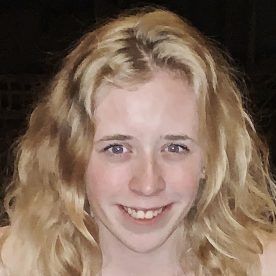 Blonde woman smiling at camera, fair skin, light eyes.