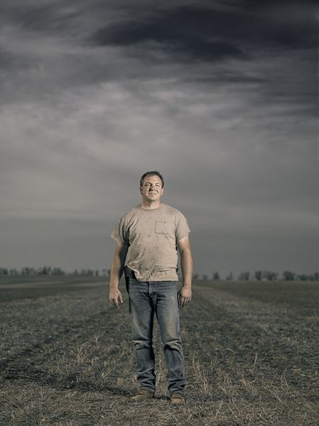 A man is standing in a field under a cloudy sky.
