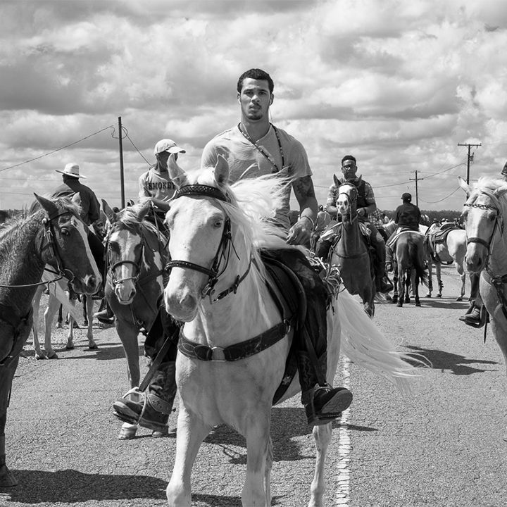 A man is riding a white horse in a black and white photo.
