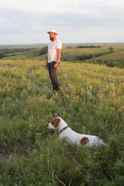 A man and a dog are standing in a grassy field.