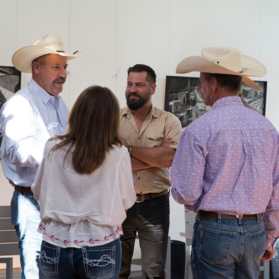A group of men wearing cowboy hats are talking to each other