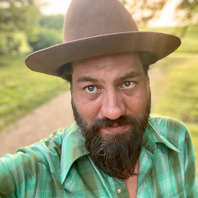 A man with a beard and a hat is taking a selfie.