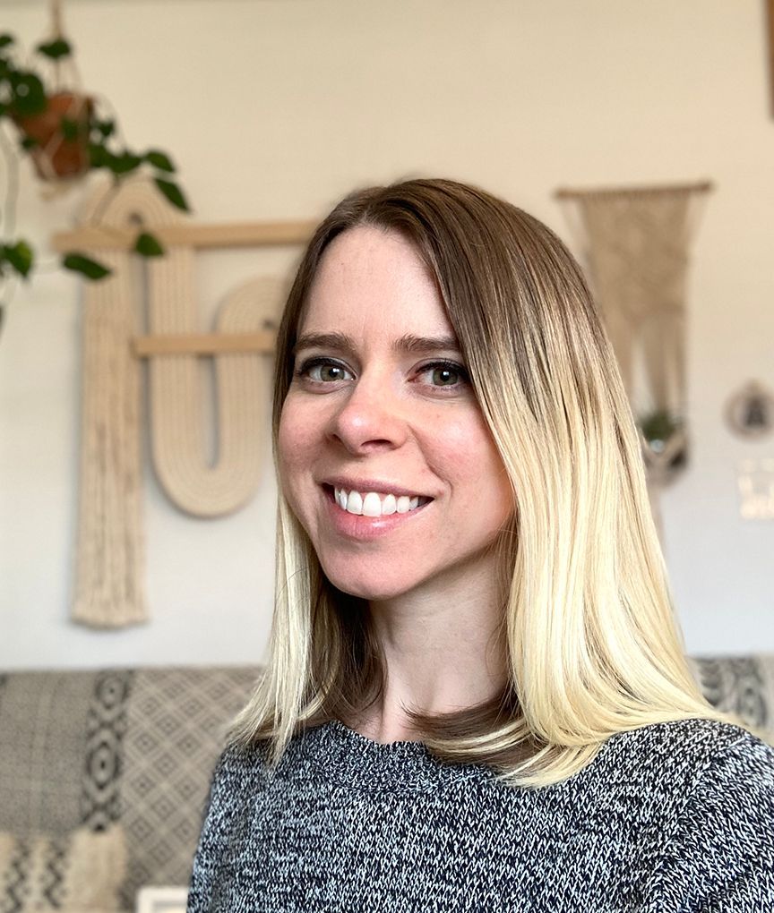 A woman is smiling for the camera while sitting on a couch in a living room.