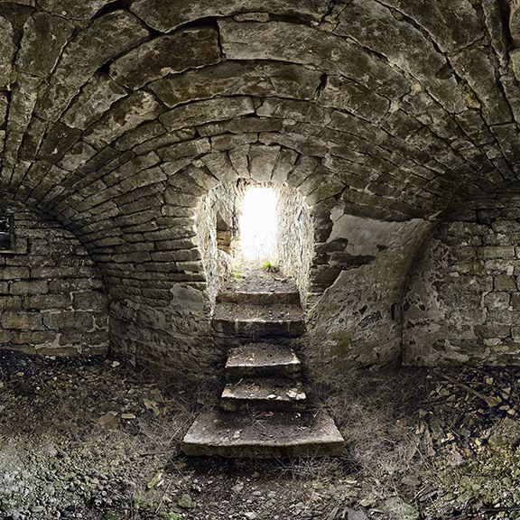 A brick tunnel with stairs leading up to a window.