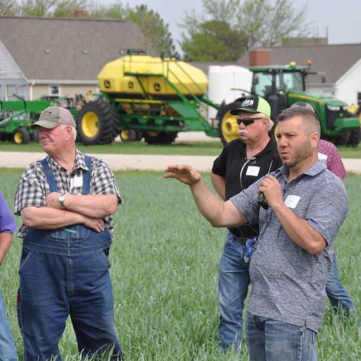 Three men are standing in a field of green grass.