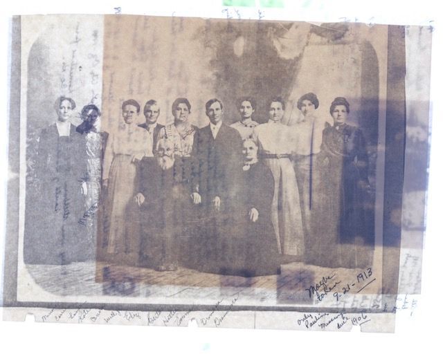 A black and white photo of a group of people with a signature on the bottom right