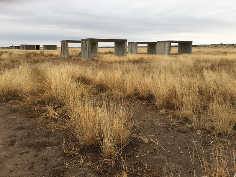 A field of dry grass with concrete structures in the background