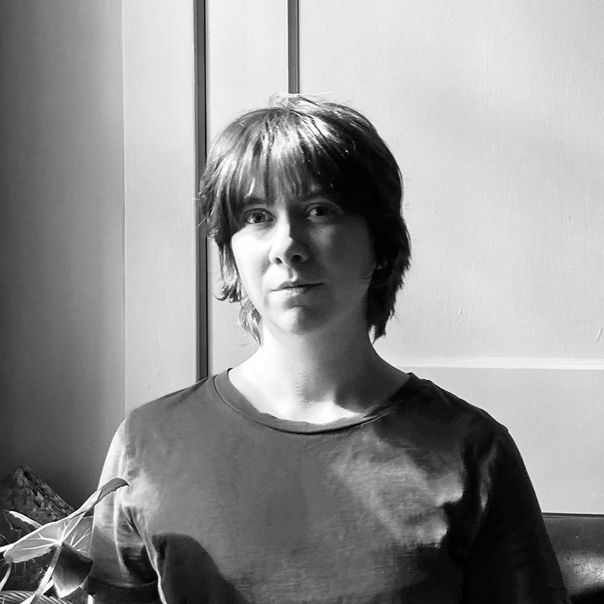 A woman is standing in front of a window in a black and white photo.