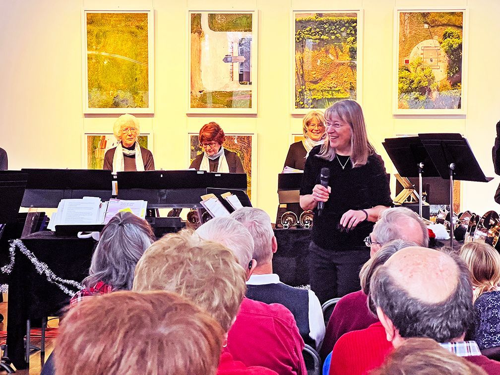 A woman smiling at the audience in front of a bell choir