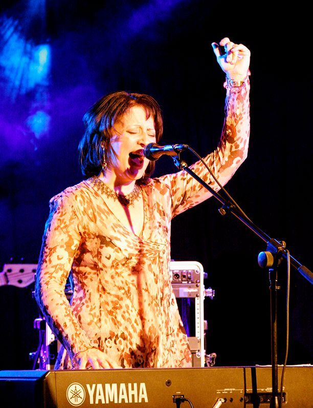 A woman singing into a microphone in front of a yamaha keyboard