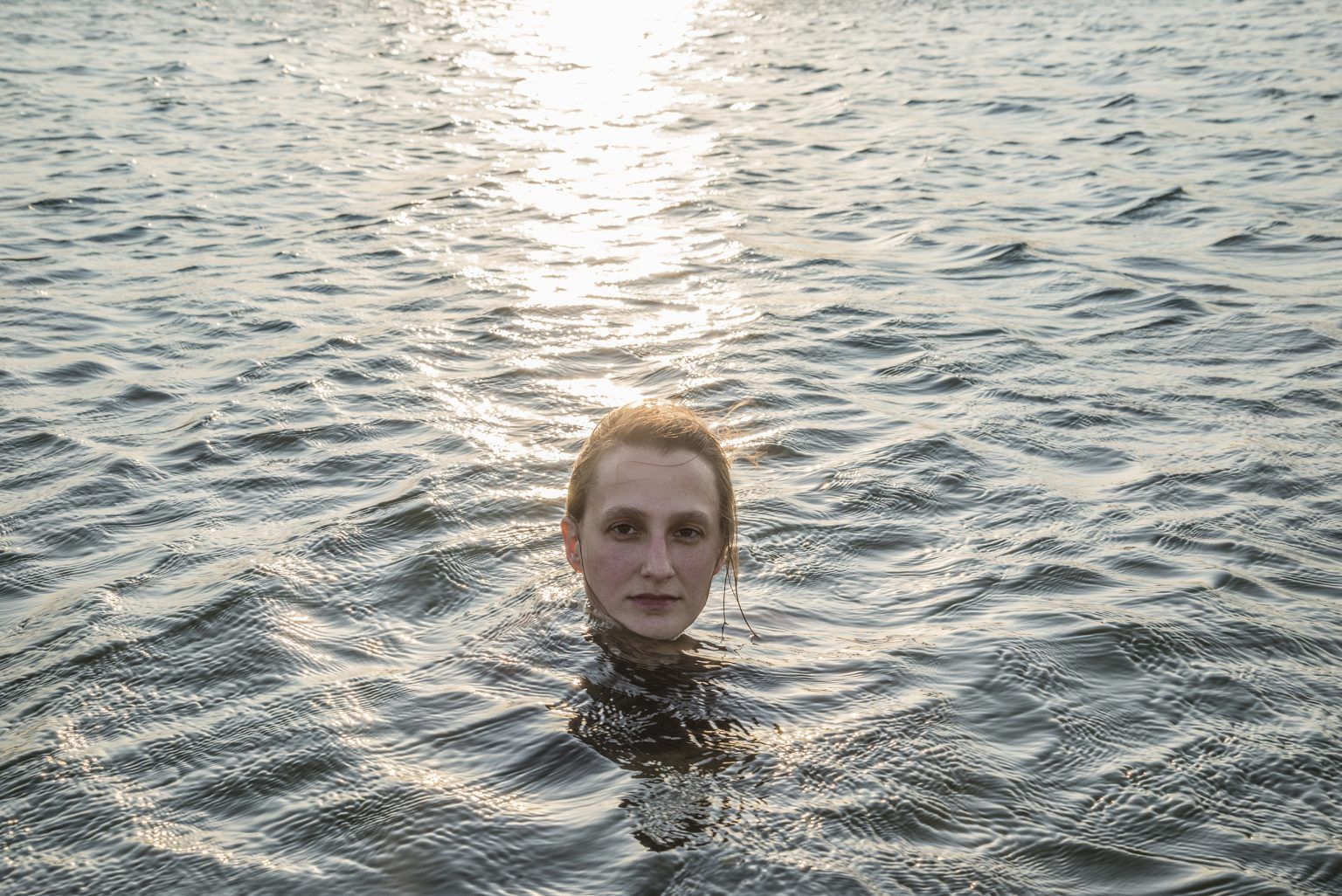 Head of a person emerging from water; neutral expression.