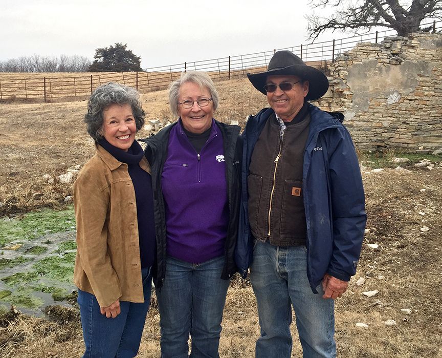 A man and two women are posing for a picture in a field