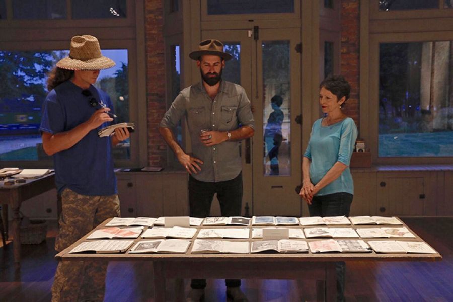 Three people are standing around a table with papers on it.
