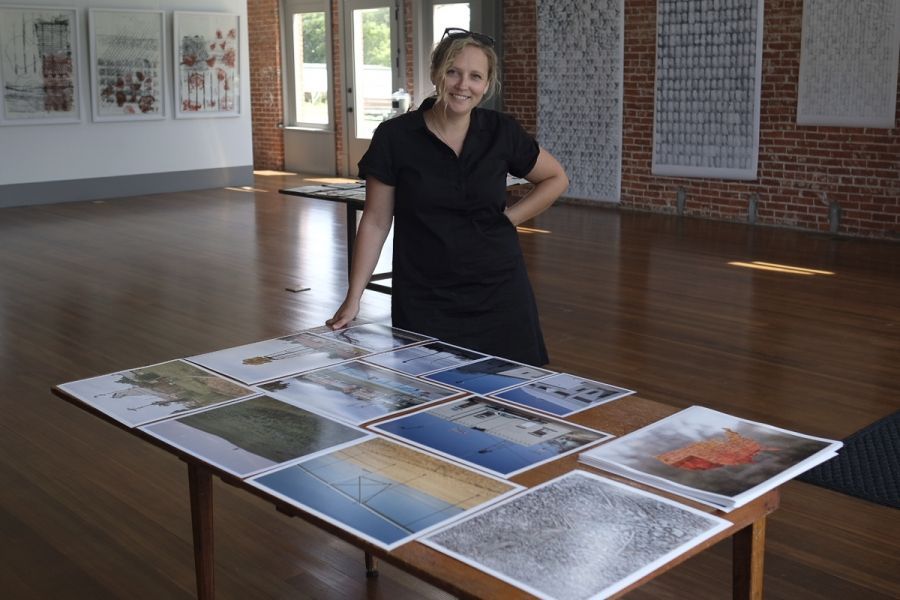 A woman is standing next to a table full of pictures