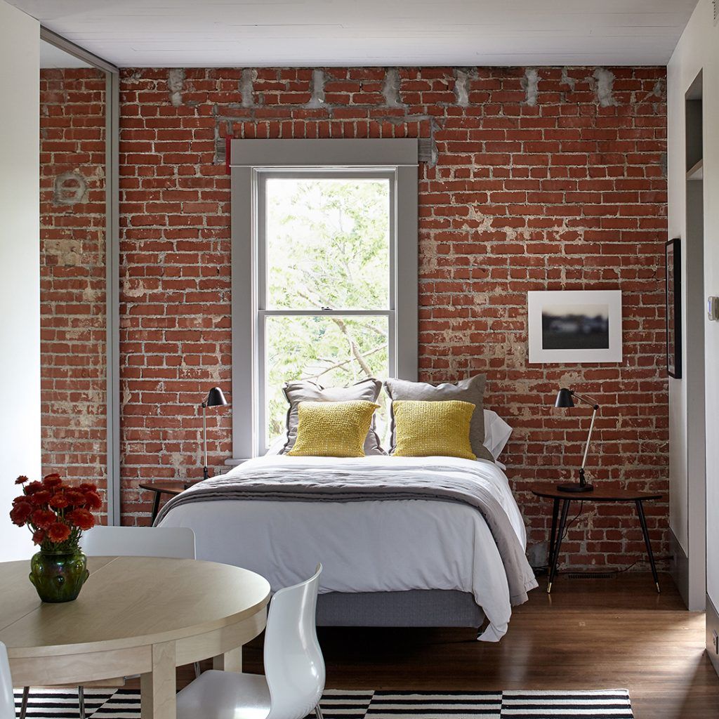 A bedroom with a brick wall and a bed