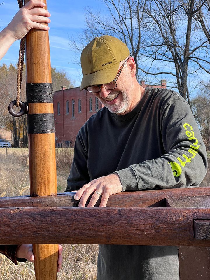 A man in a carhartt shirt is standing next to a wooden pole.