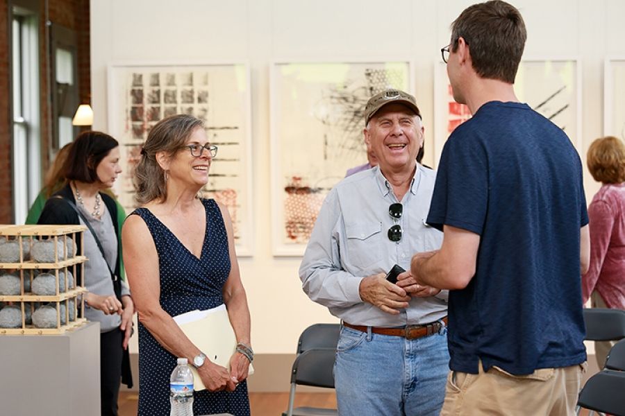 A group of people are standing in a room talking to each other.
