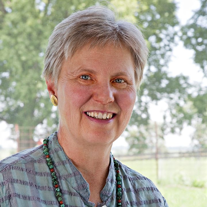 A woman wearing a green necklace is smiling for the camera