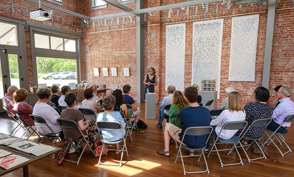 A woman is giving a presentation to a group of people sitting in chairs.