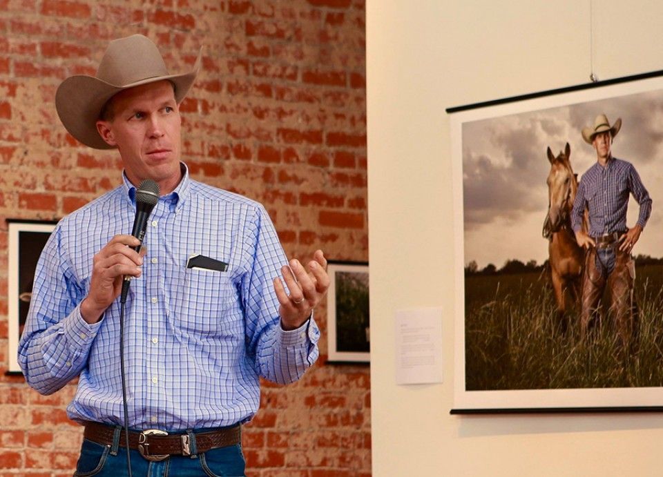 A man in a cowboy hat is speaking into a microphone