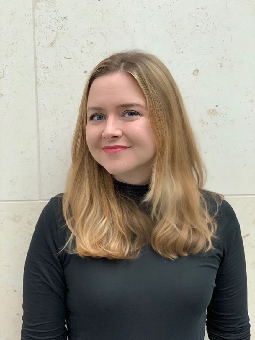 A woman with long blonde hair is wearing a black shirt.