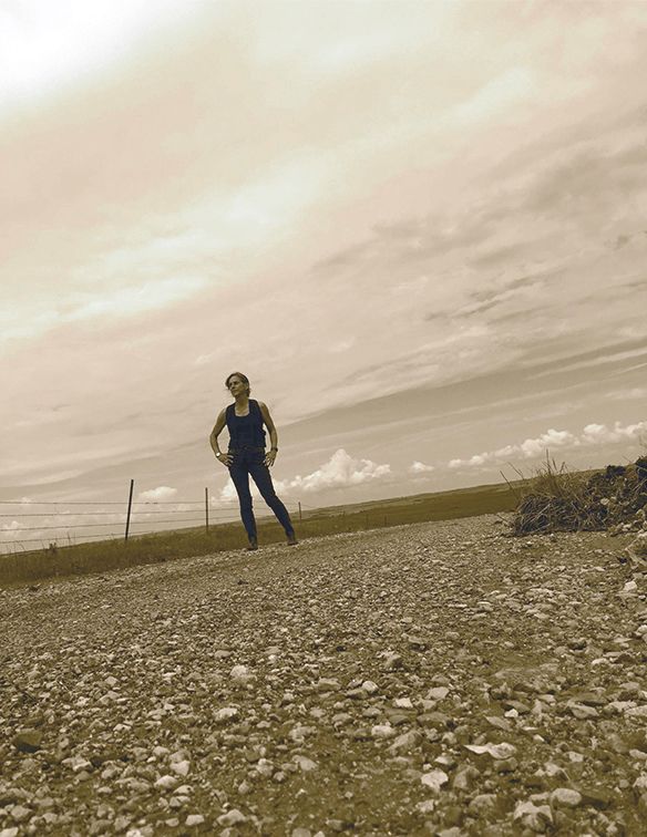 A woman is standing on a gravel road.