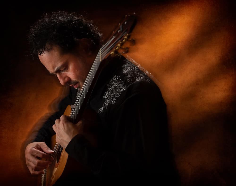 A man is playing a guitar in a dark room.