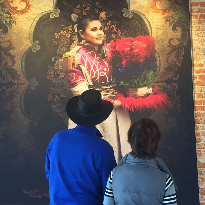 A man and woman are looking at a painting of a woman holding flowers