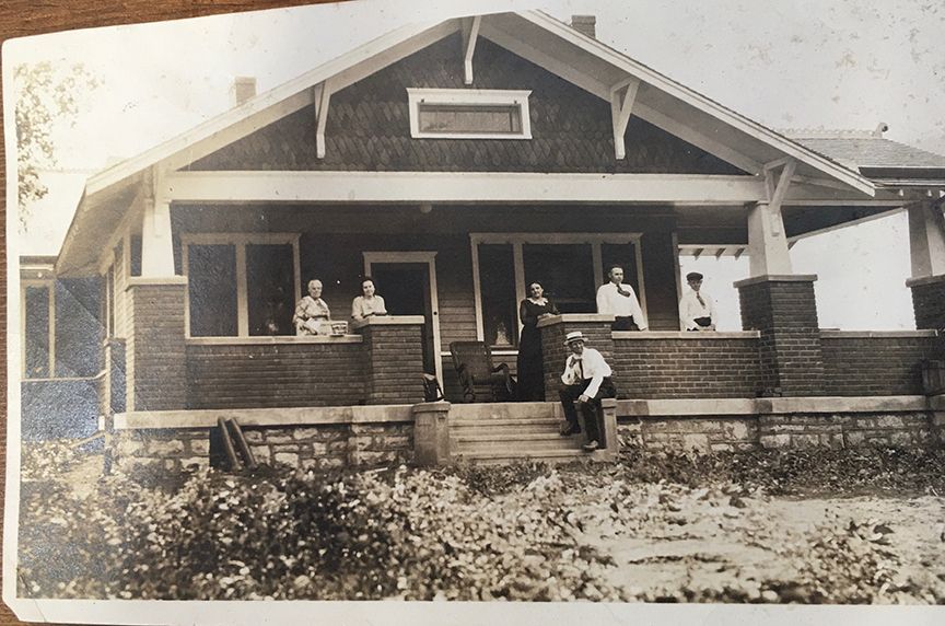 A black and white photo of a house with people on the porch