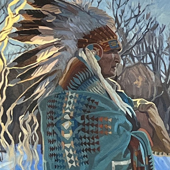 Native American man in headdress and patterned blanket, standing outdoors.