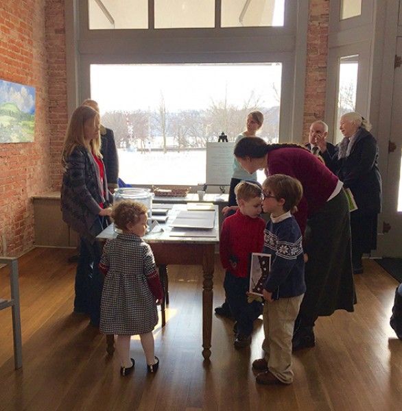 A group of people are standing around a table talking to each other