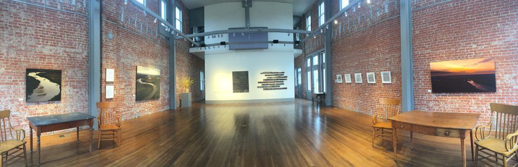 A long hallway with tables and chairs and a brick wall.
