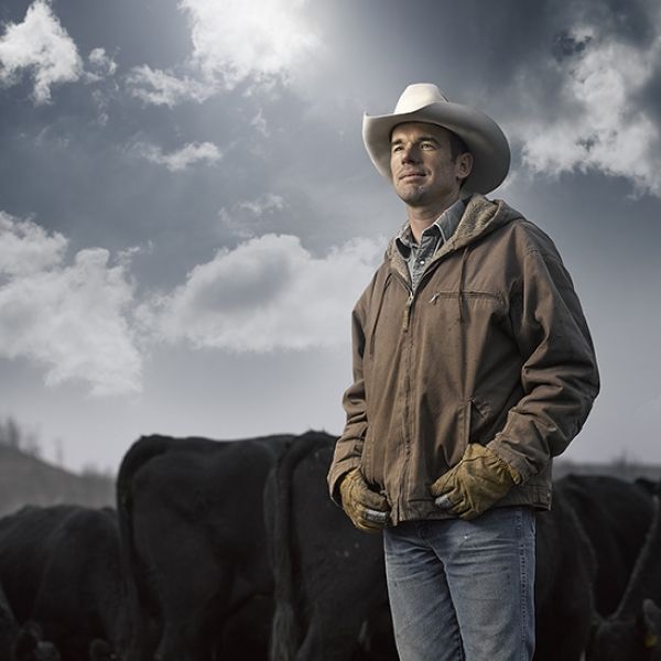 A man in a cowboy hat stands in front of a herd of cows