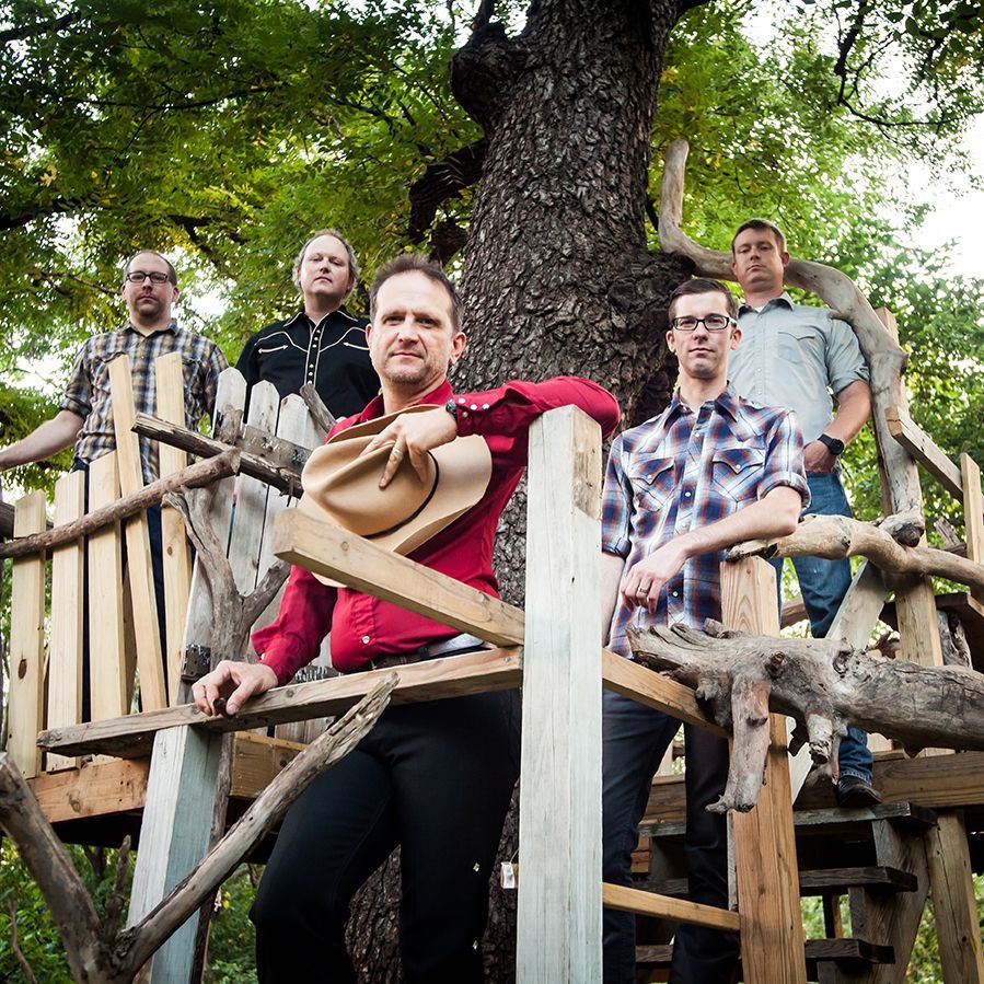 Country band posing in a treehouse, wearing casual attire.
