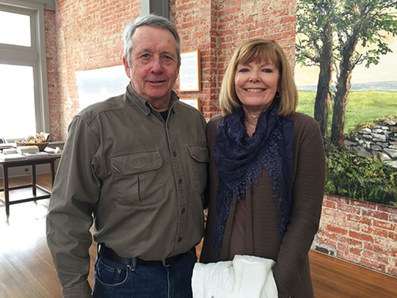 A man and a woman are posing for a picture in front of a painting.