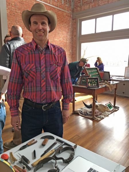 A man wearing a cowboy hat is standing next to a table with tools on it