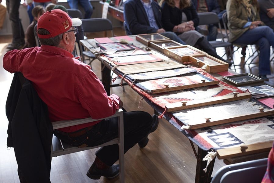 A man in a red hat is sitting at a table with pictures on it