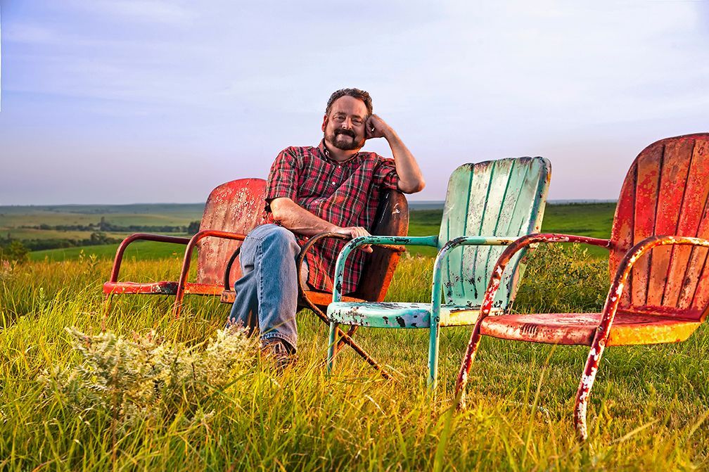 A man is sitting on a chair in a field.