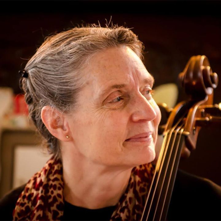 A group of people playing violins and cello in a room