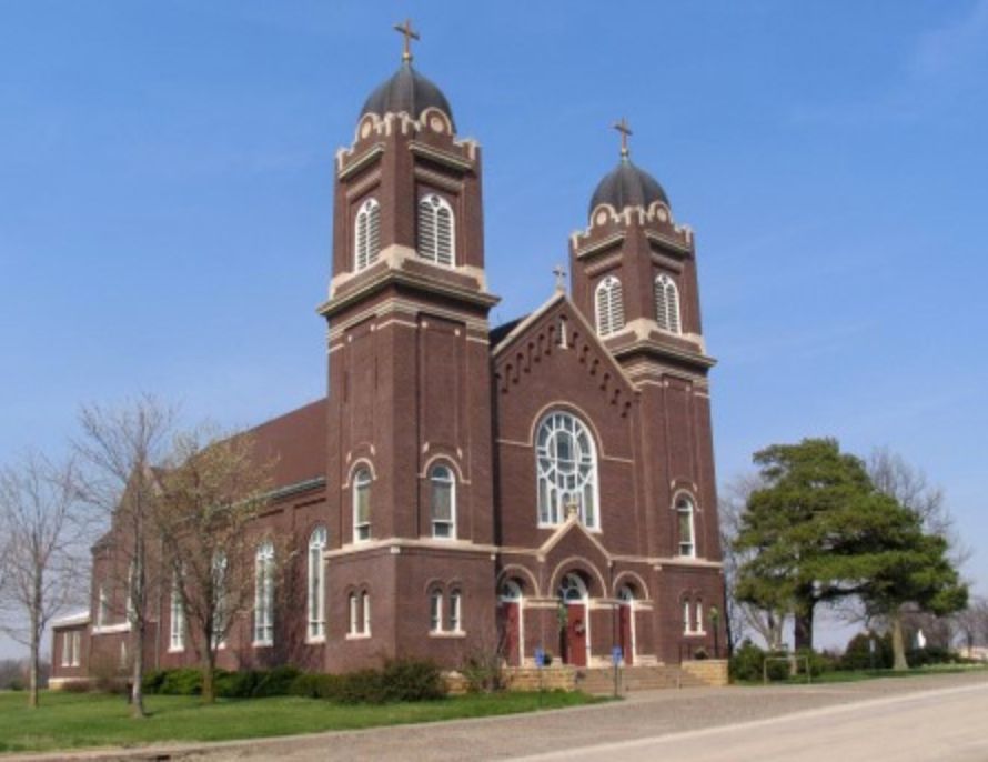 Brick church with two towers and crosses against a blue sky.