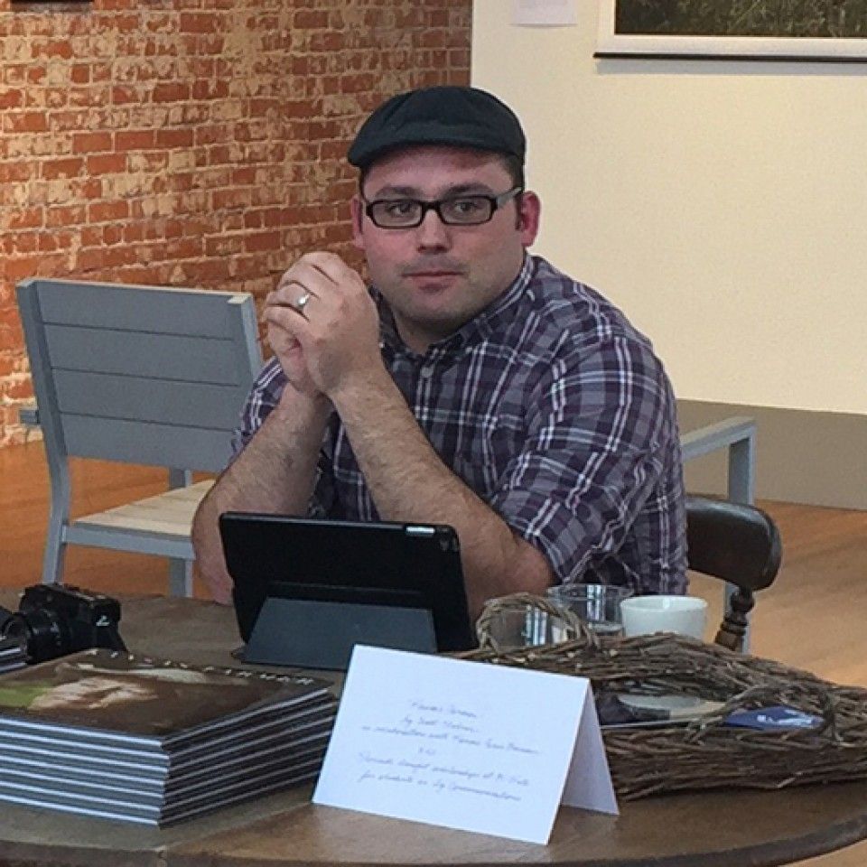 A man wearing glasses sits at a table with a tablet