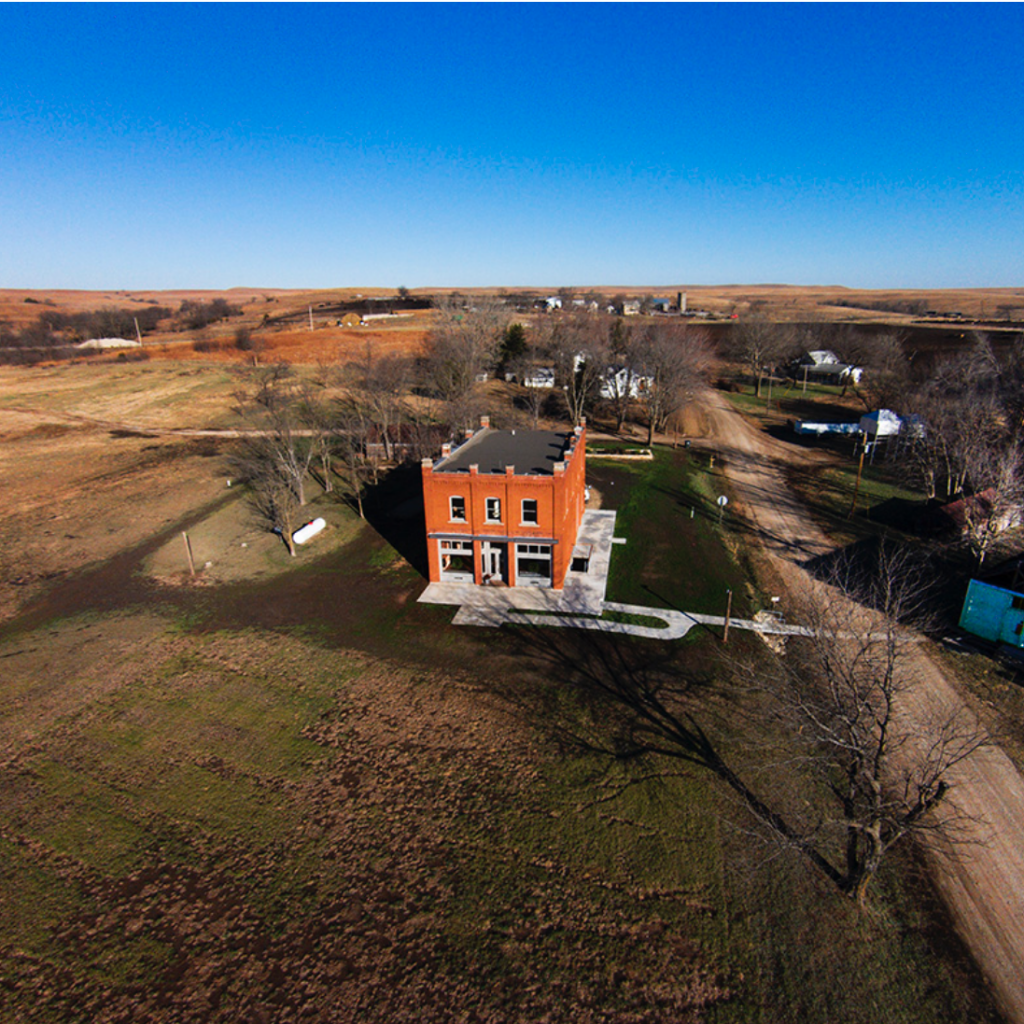 An aerial view of a brick building in the middle of a field