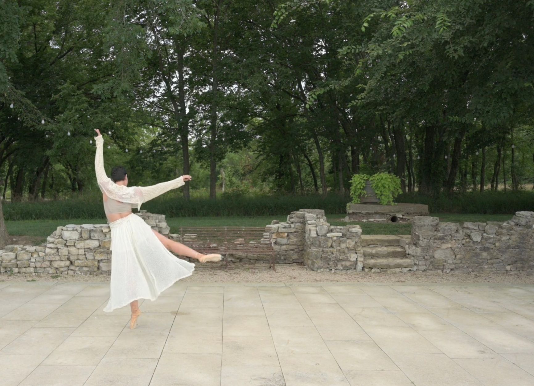 Woman dancing gracefully outdoors with a white dress.